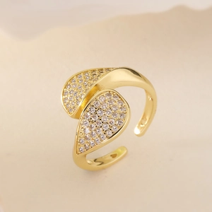 Eleganter goldener Blattring mit Zirkonia-Kristallen auf beigem Hintergrund