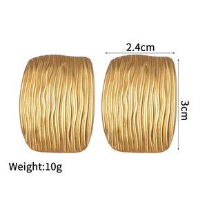 Detail of gold oval earrings featuring wave texture and dimensions 2.4cm by 3cm