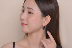 Detail view of a model wearing the elegant black oval stone earrings in a stylish setting