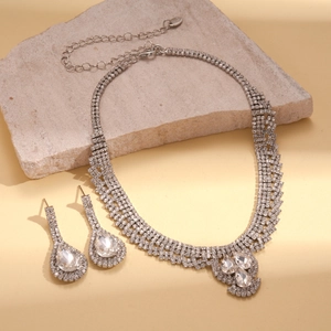 Détail d'un ensemble collier et boucles d'oreilles en strass argentés avec gouttes