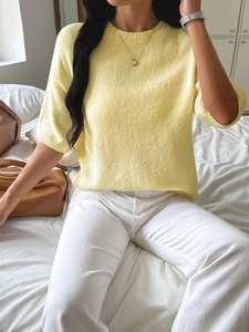 Close-up of a yellow knit sweater featuring soft texture and stylish round neckline