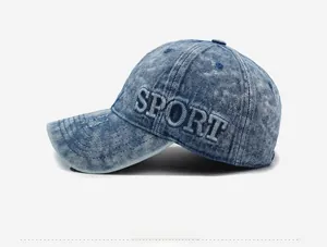 Detail of SPORT embroidery and distressed holes on light blue washed denim baseball cap