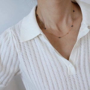 Collana di perline blu stile pittura a olio con accenti dorati indossata dalla modella