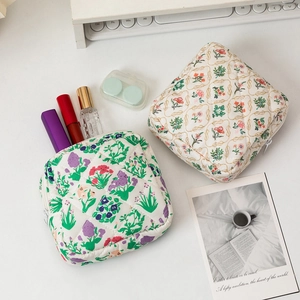 Quilted floral sanitary napkin storage bags and portable cosmetic pouches on white desk