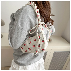 Detail of strawberry print corduroy shoulder bag with pleated strap and bow accents