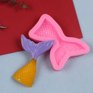 Detailed pink silicone mold for mermaid tail cakes with purple and yellow fondant examples