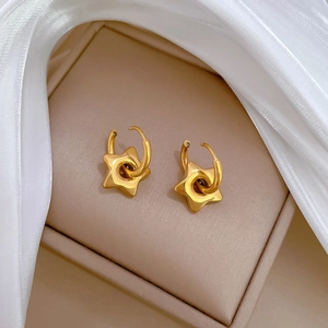 Macro shot of gold star-shaped earrings placed in a premium beige velvet jewelry box