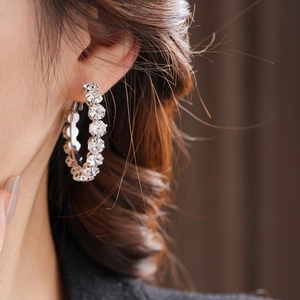 Close-up of silver-tone hoop earring with shimmering rhinestones on female model
