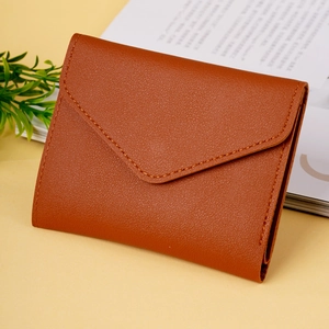 Close-up of tan lychee grain leather envelope wallet with neat stitching on a desk