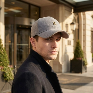 Gray herringbone baseball cap with metallic R logo worn by a man in a classic coat