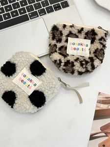 Plush leopard and cow print mini coin purses with zipper closure on a white desk