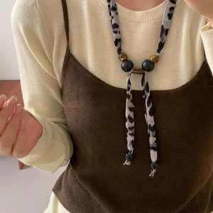 Close-up of leopard print fabric beads and wood bead pendant on a long necklace