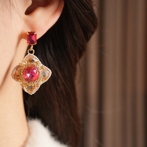 Close-up of vintage gold earrings with red gemstones and pearls on a model ear