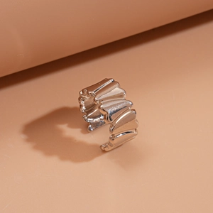 Détail d'une bague ouverte argentée avec textures plissées 3D et ondulations chic