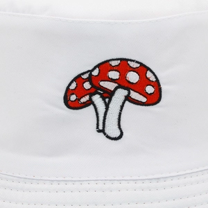 White bucket hat featuring red mushroom embroidery in a reversible casual style
