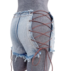 Dettaglio di pantaloncini di denim azzurro con allacciatura laterale e lacci in cuoio