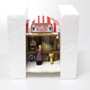 Detailed view of miniature popcorn wagon Christmas village scene in protective foam packing
