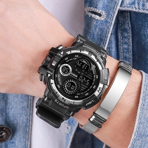 Black digital sports watch and silver bracelet worn on wrist with casual denim jacket