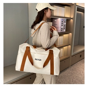 Close-up of a large canvas travel bag with brown straps and HAYUN text on white fabric