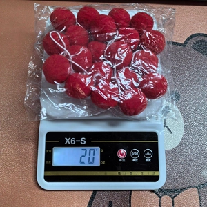 Detailed view of red felt balls on a scale showing a 20g weight for Christmas decor