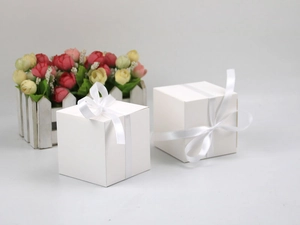 Detail of white square wedding candy boxes with elegant satin ribbons and bows