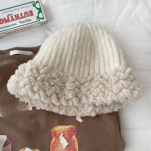 Detailed texture of beige knitted bucket hat with plush faux rabbit fur brim for winter