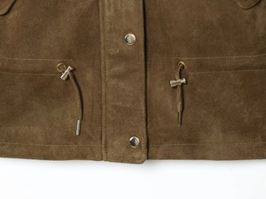 Détail de veste en suédine marron avec œillets métalliques dorés et cordon de serrage