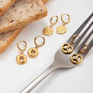 Detailed close-up of golden snack-themed earrings featuring waffle and pretzel shapes