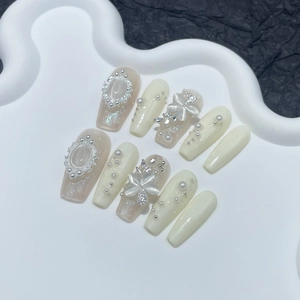 Handmade press-on nails with pearls and gems on a wave stand over black background