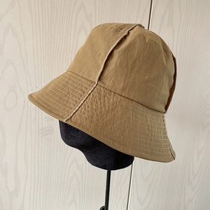 Khaki waterproof nylon bucket hat for men and women on a display stand with minimalist design