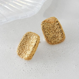 Textured gold-tone rectangular stud earrings with a modern matte lava surface design