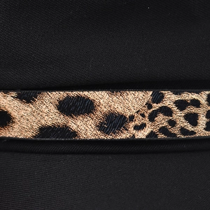 Detailed close-up of leopard print strap on black twill fabric of the beret cap