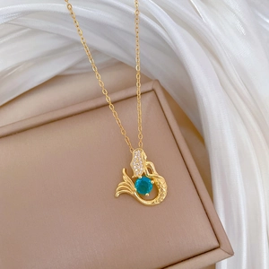 Detail view of a mermaid necklace with a green gemstone and crystals on silk fabric