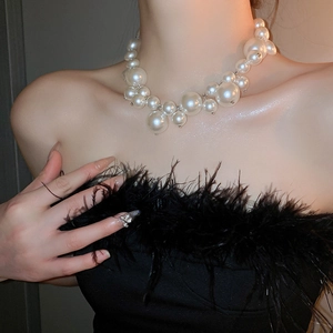 Close-up of irregular white pearl cluster necklace on a model in dramatic lighting