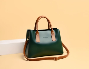 Detail of dark green tote bag featuring brown handles and gold hardware on geometric stand