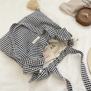 Detail of checkered canvas tote bag with beige tassel and textured fabric surface