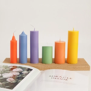 Minimalist colorful cylinder pillar candles in diverse heights on wooden display stand