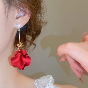 Macro detail of red petal tassel earring with shimmering crystal on a model