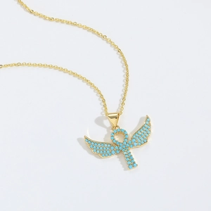 Macro shot of gold Ankh cross pendant with angel wings and turquoise blue bead inlay