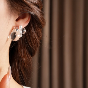 Close-up of transparent bubble stud earrings with small pearls and metal beads on ear