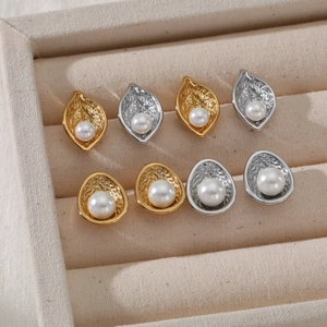 Gold and silver leaf and oval textured earrings with pearls on a beige velvet tray