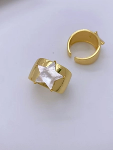 Flat lay of gold plated wide band rings featuring a star-shaped shell inlay detail