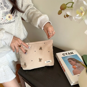 Detailed texture of beige corduroy makeup bag with cute vintage bear pattern print