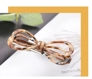 Detailed shot of tortoiseshell acetate bow hair clip with polished metallic base