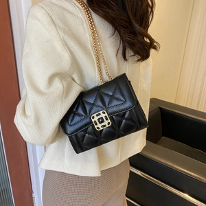 Elegant black quilted leather chain bag with gold hardware worn by a model in casual style