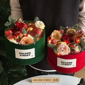 Luxe velvet Christmas gift box with fresh roses, apples, and festive fairy lights