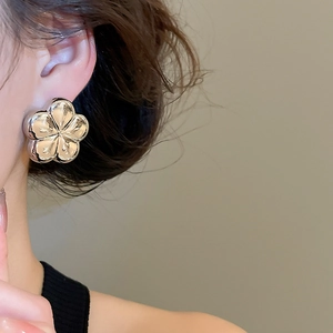 Detail view of mirror-finish silver five-petal flower stud earring on a model