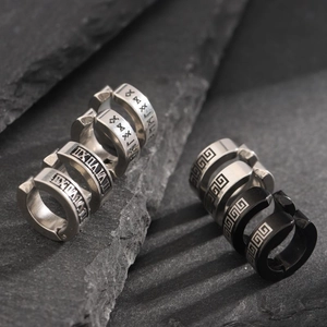 Macro shot of silver and black stainless steel ear cuffs with Roman numerals on rock