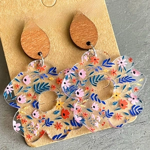 Detailed close-up of acrylic floral earrings with natural wood studs on a jewelry card