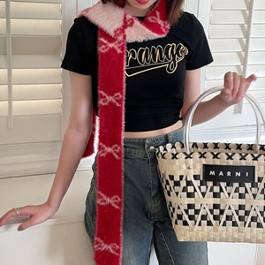 Detail showing red and pink plush scarf with bow patterns on a casual model outfit